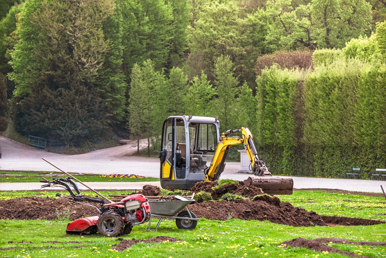 Mini-bagger en tuinwerktuigen bij tuinaanleg in Warnsveld door Sunny Hoveniers, met nieuw aangelegd terras en groen.